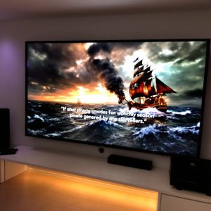 AI сказочник генерирует историю о пиратах на большом экране телевизора. На экране - корабль, плывущий по бурному морю